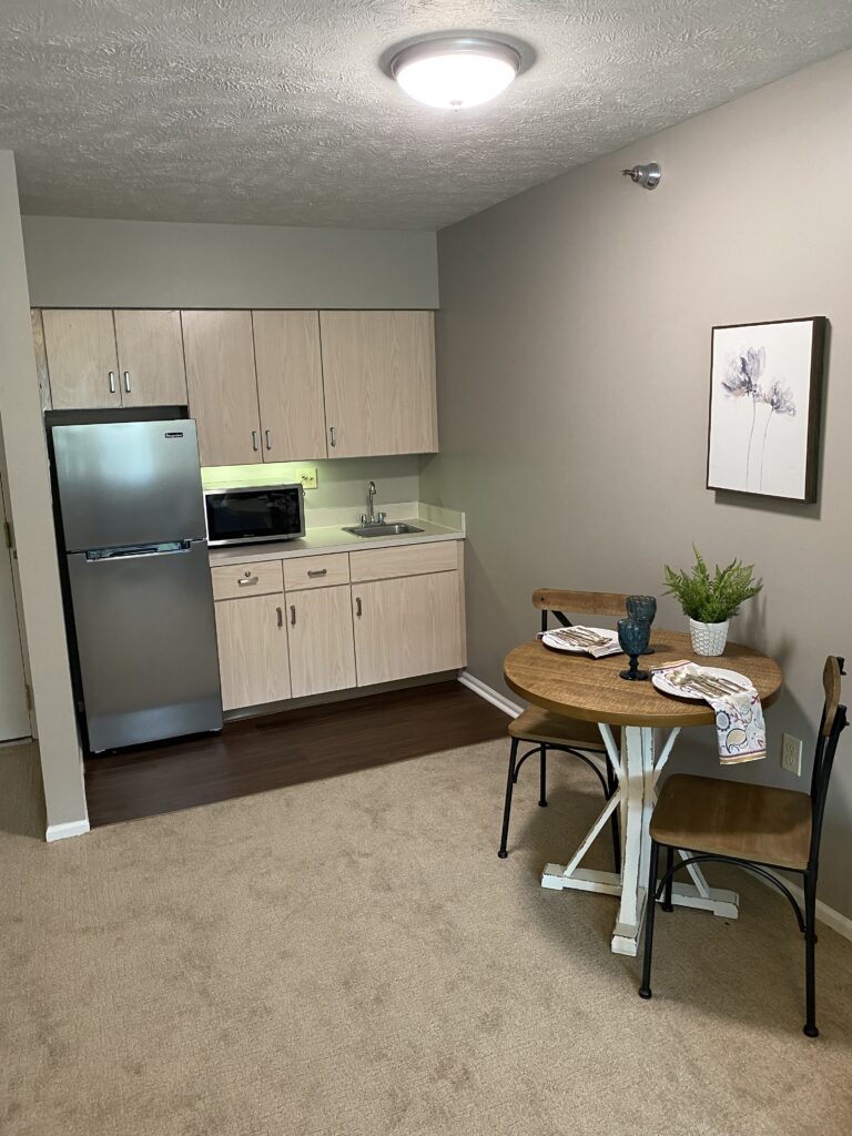 kitchenette with a microwave, fridge and sink near a table and chairs