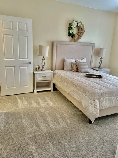 A model apartment bedroom with a bed and nightstands at a senior community in Fort Worth, Texas.