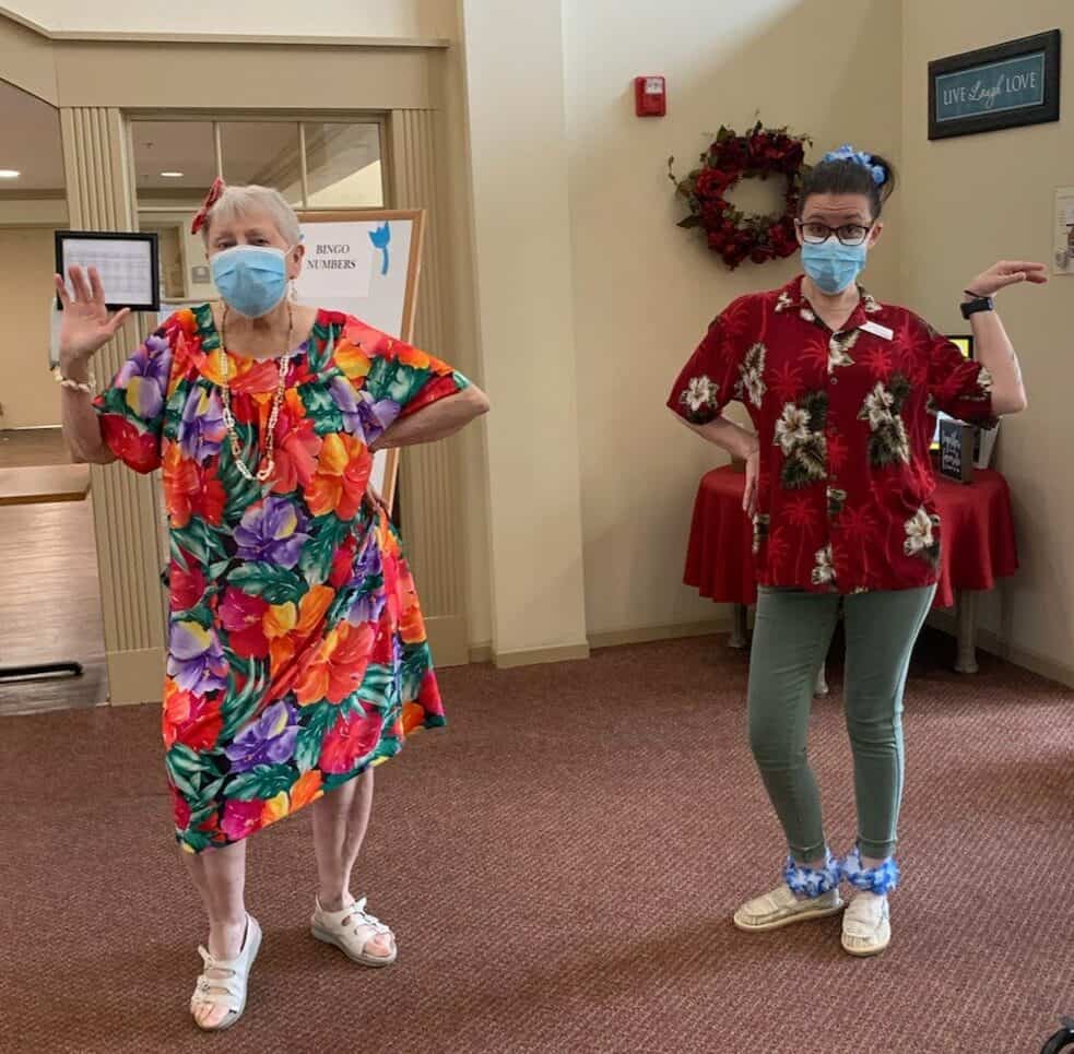 Senior living resident and employee dancing in Hawaiian outfits at a senior living community in Lincoln, Nebraska.