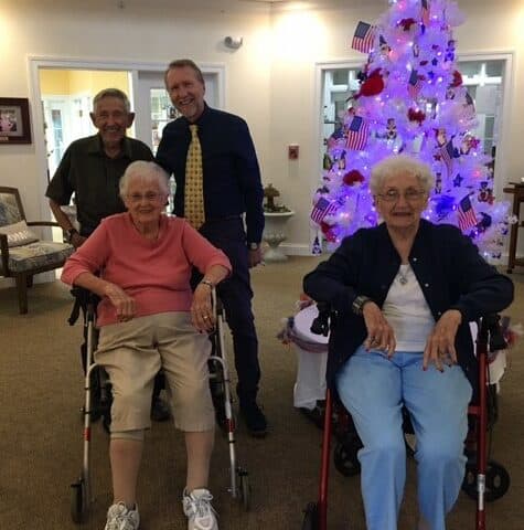 Four seniors pose in front of a Christmas tree at a senior living community in Rochester, Indiana