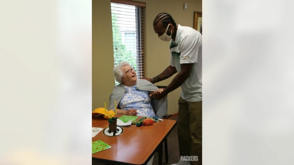 Senior living employee helps resident with games.