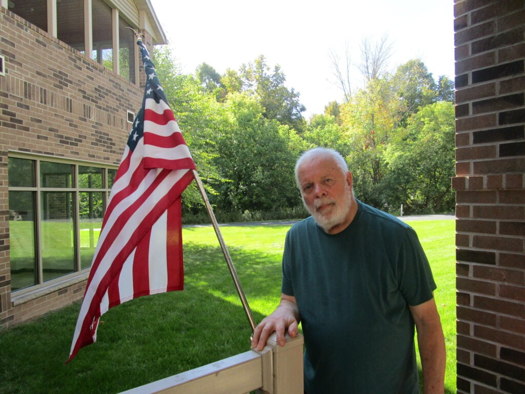 senior man stands in front of the American flag at Brookview Meadows