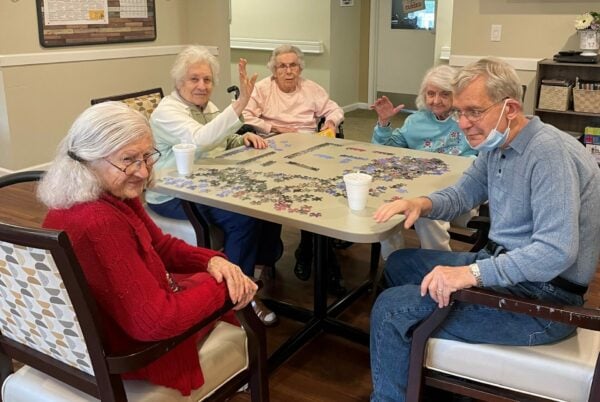 group of seniors solve a puzzle together at a table