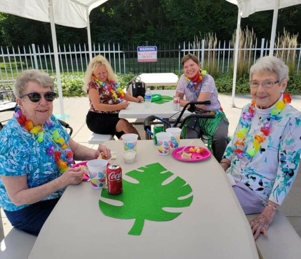four senior women enjoy treats during a luau party at georgetowne place senior living