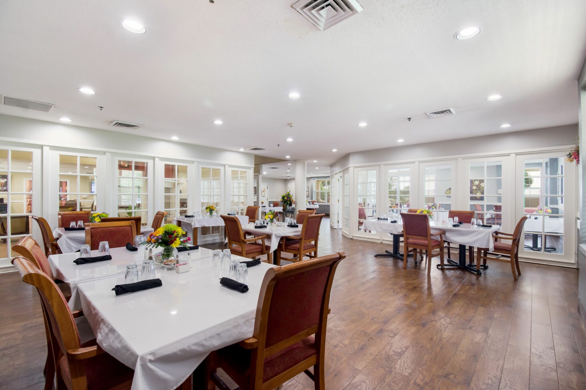 Dining room with white tablecloths and high back chairs at a senior living community