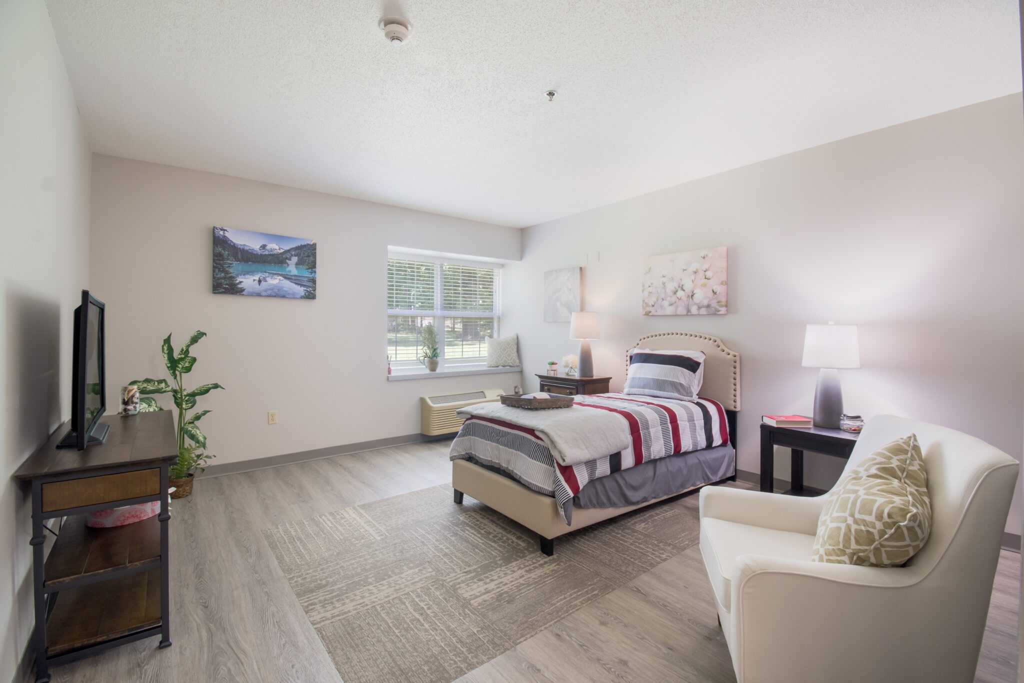 senior apartment bedroom with a TV, bed and chair