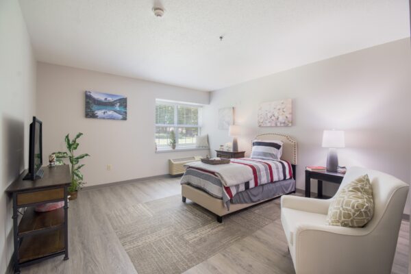 senior apartment bedroom with a TV, bed and chair
