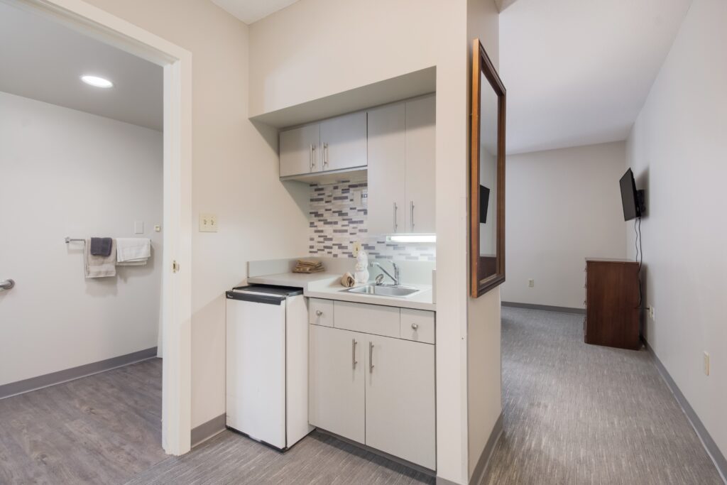 small kitchenette, including a sink and fridge, within a senior apartment
