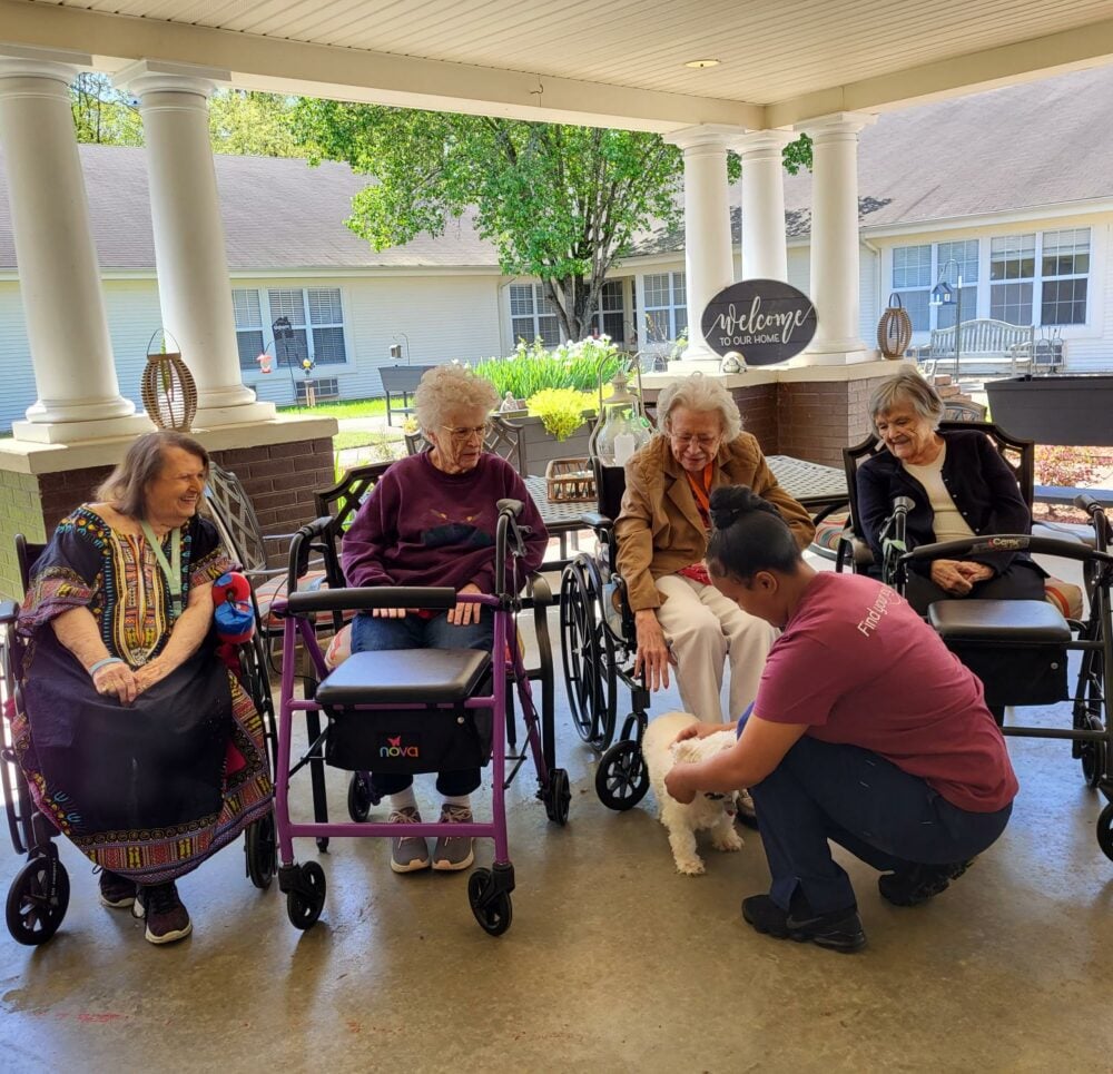 group of senior women admire a small white dog