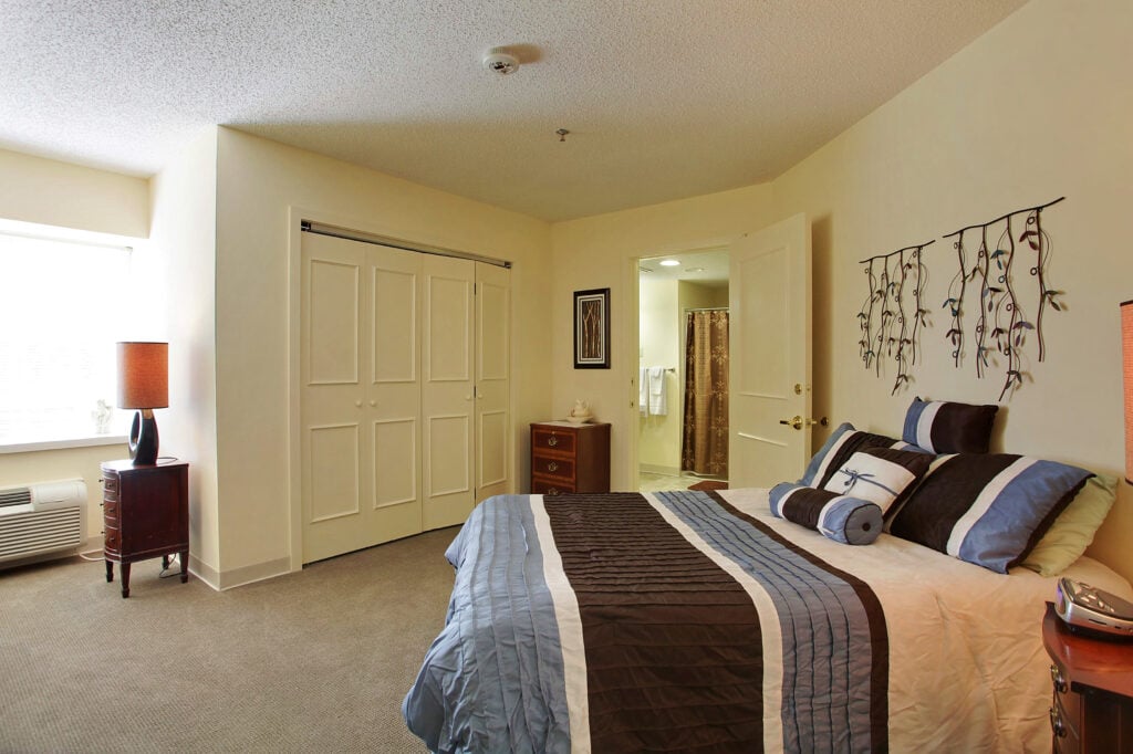 apartment bedroom with a large bed, closet and door to bathroom