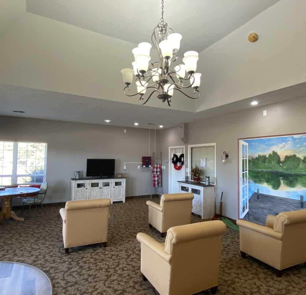 Activity center at the waterford at woodbridge includes a TV, chairs and a chandelier