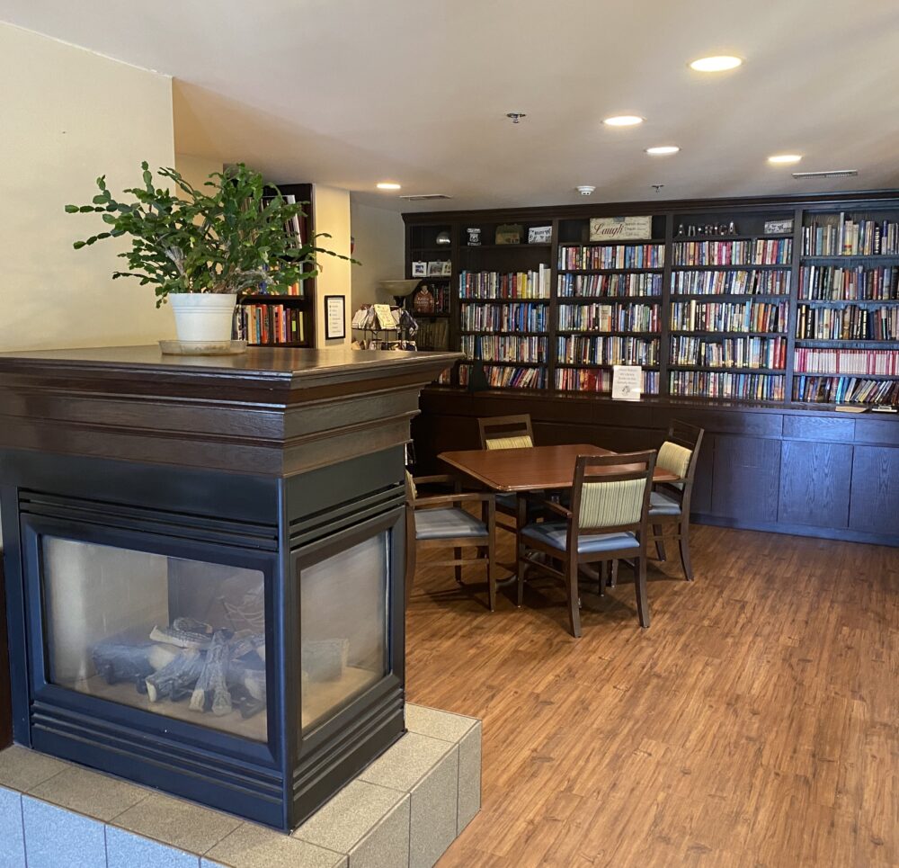 library with large bookshelf full of books, a seating area and a fireplace