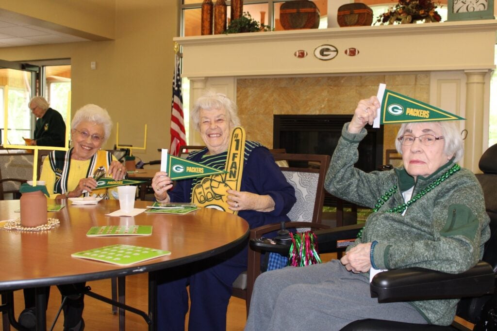 three senior women smile and cheer for the Green Bay Packers at Brookview Meadows