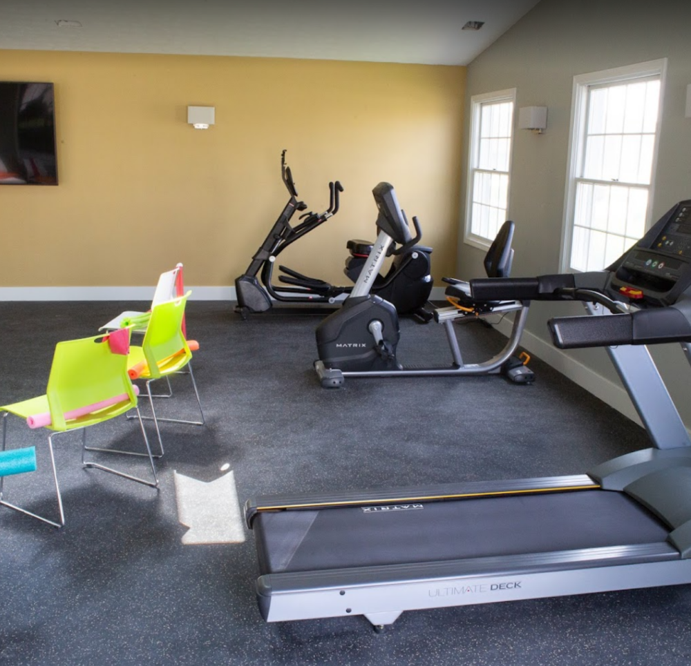 Fitness center with treadmill, bikes and chairs near a TV