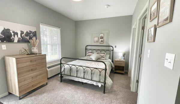 senior living apartment bedroom with a bed, dresser and closet
