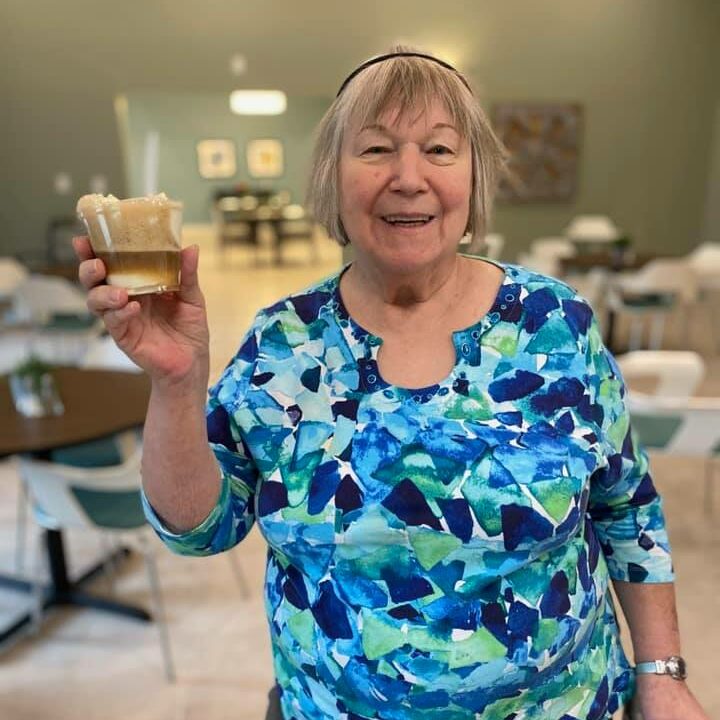 senior woman smiles while holding a root beer float