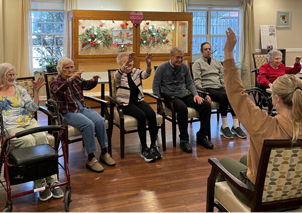 A group of seniors enjoying a seated exercise class at a Sonida Senior Living memory care community.