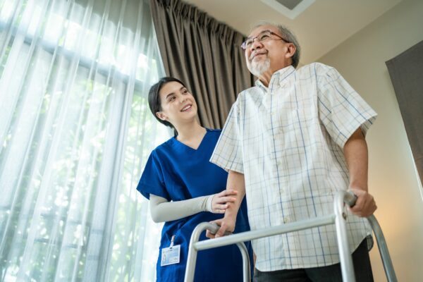 Asian Senior elderly disabled man patient walking slowly with walker at nursing home care.