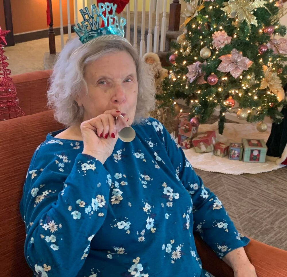 senior woman celebrates the new year with a festive hat and noise maker