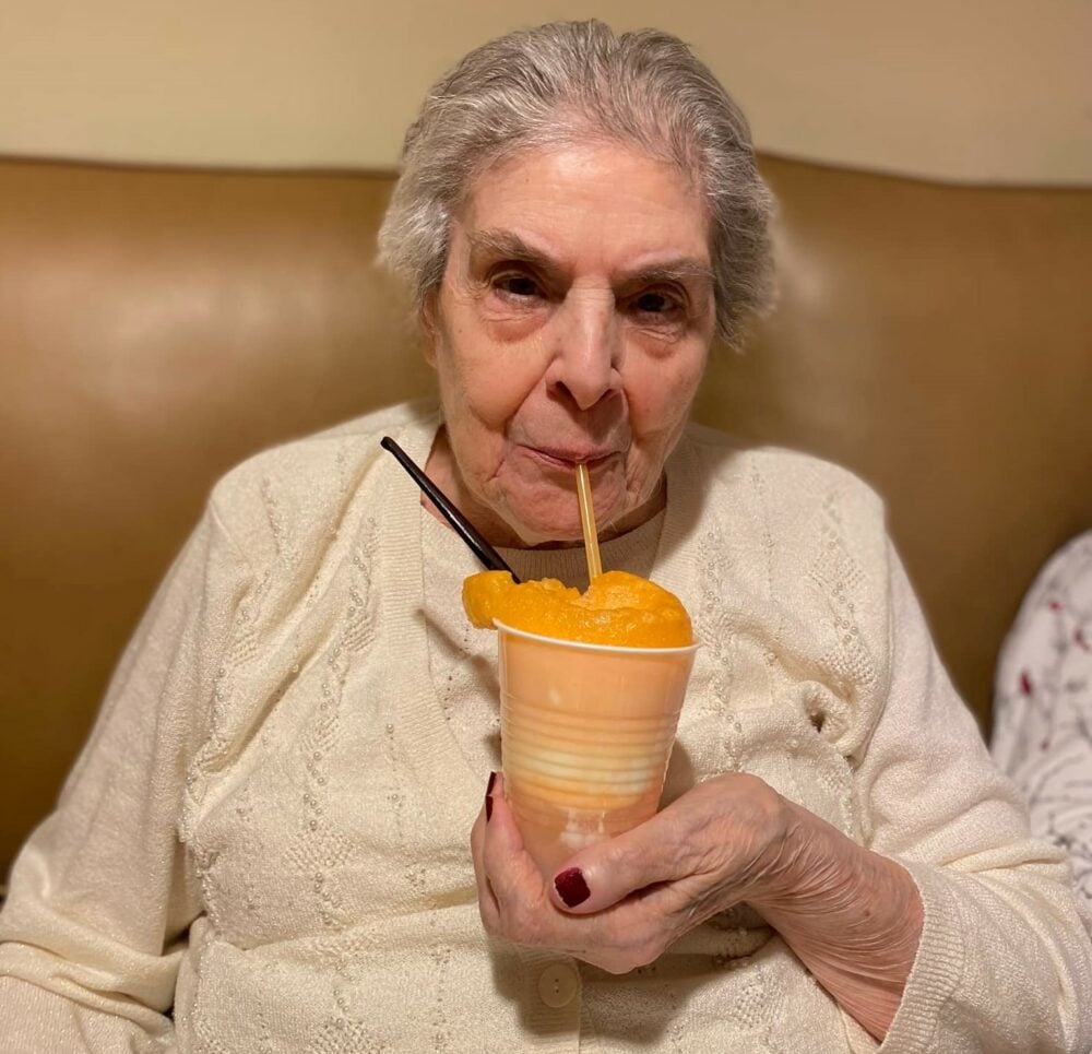 senior woman drinks an orange slushie
