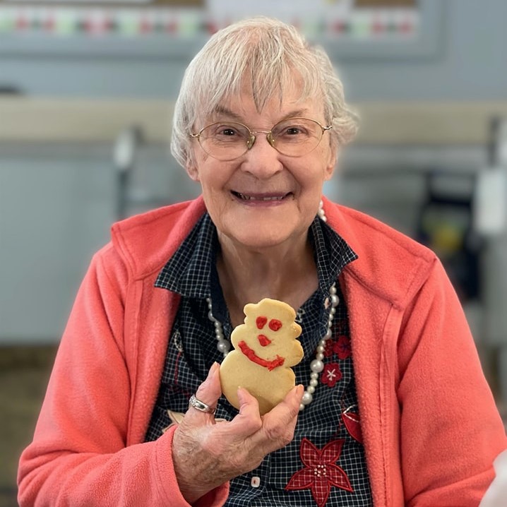 senior woman smiles and holds a decorated cookie