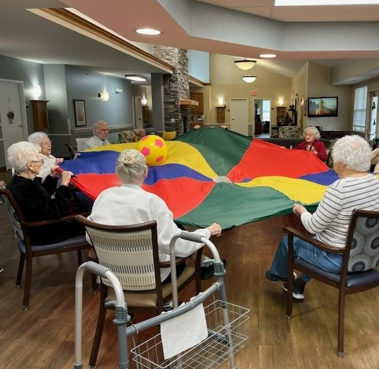 group of seniors play with a parachute and ball in the middle