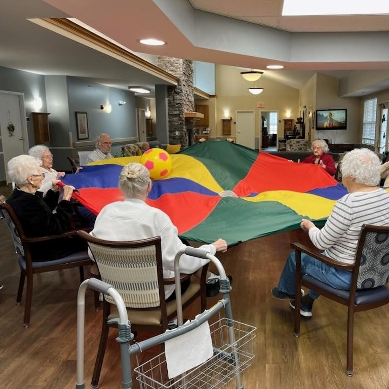group of seniors play with a parachute and ball in the middle
