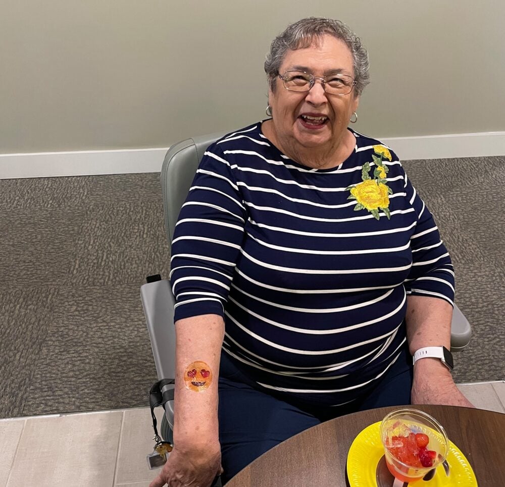 senior woman smiles while showing off her temporary tattoo on her arm