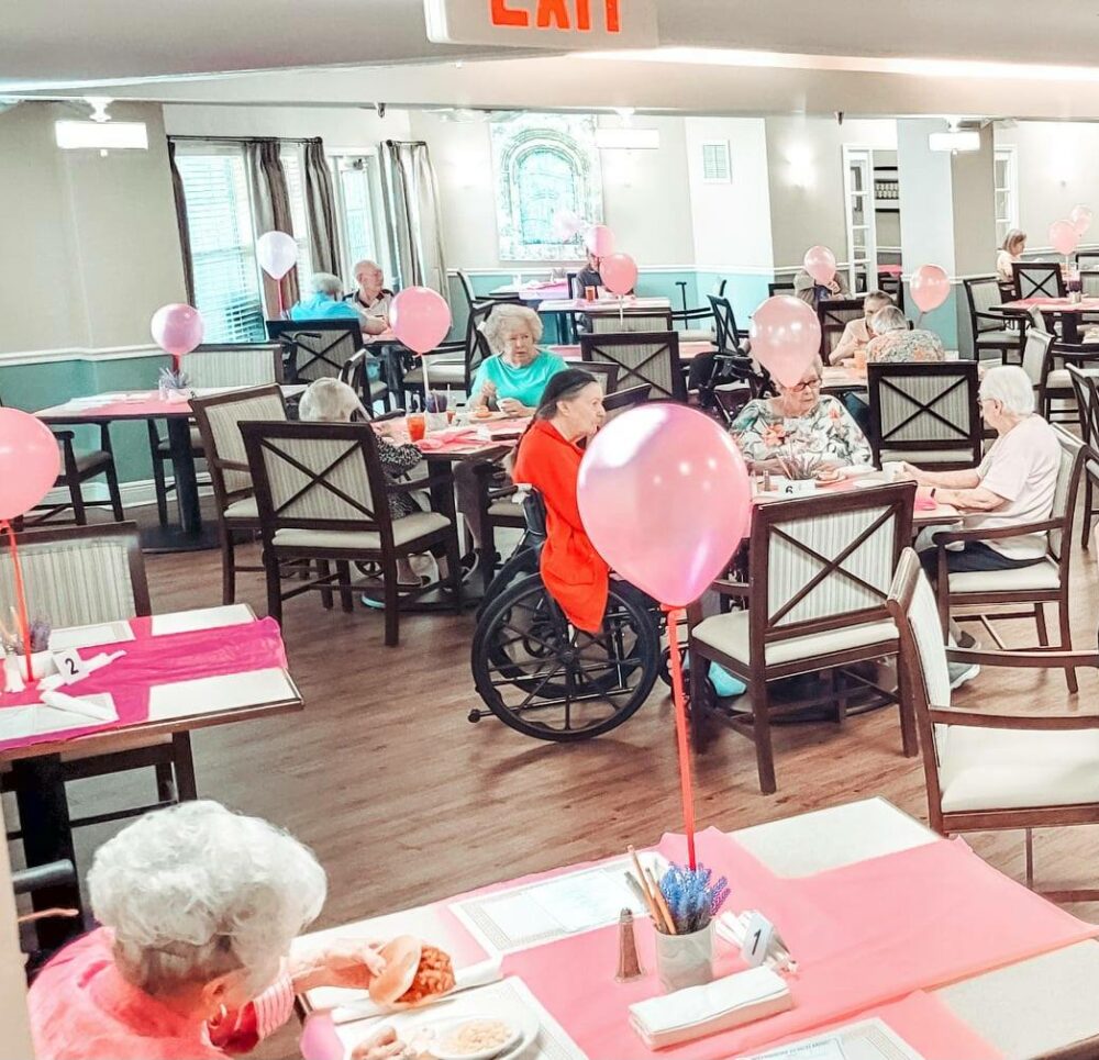 dining room decorated for valentines day with pink balloons and pink tablecloths