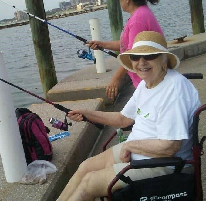 senior woman smiles while holding a fishing pole