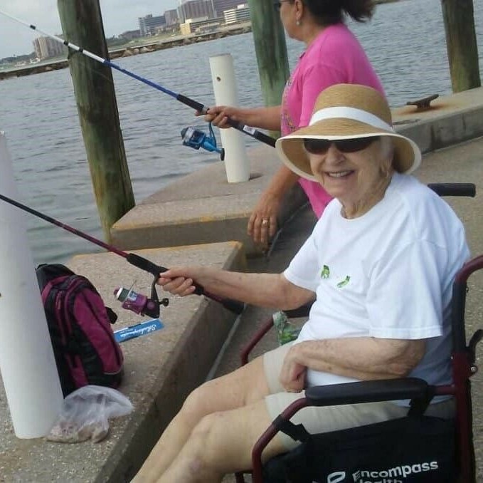 senior woman smiles while holding a fishing pole