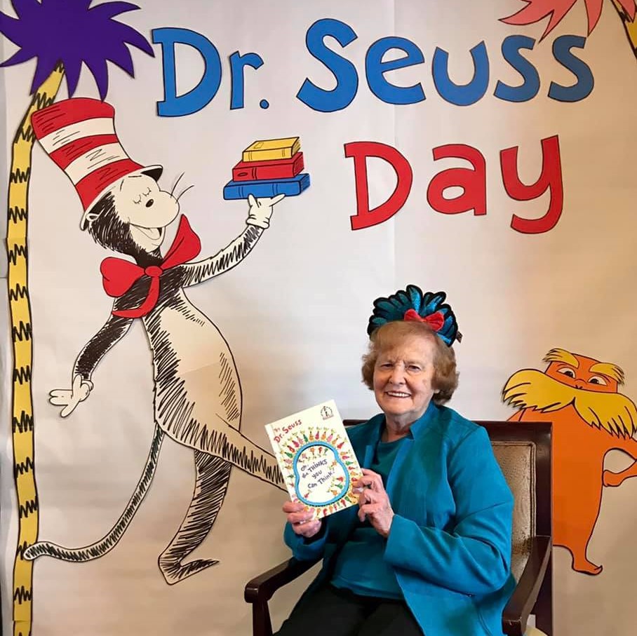 senior woman smiles while holding a Dr. Seuss book on Dr. Seuss Day