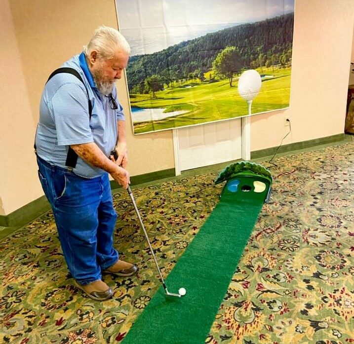 senior man plays miniature golf inside the waterford at fort worth