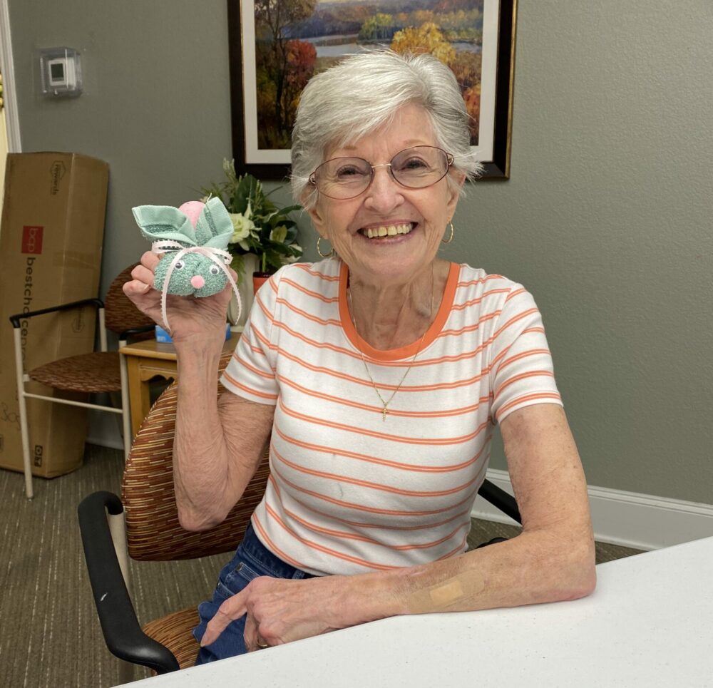 senior woman smiles while showing off her bunny craft