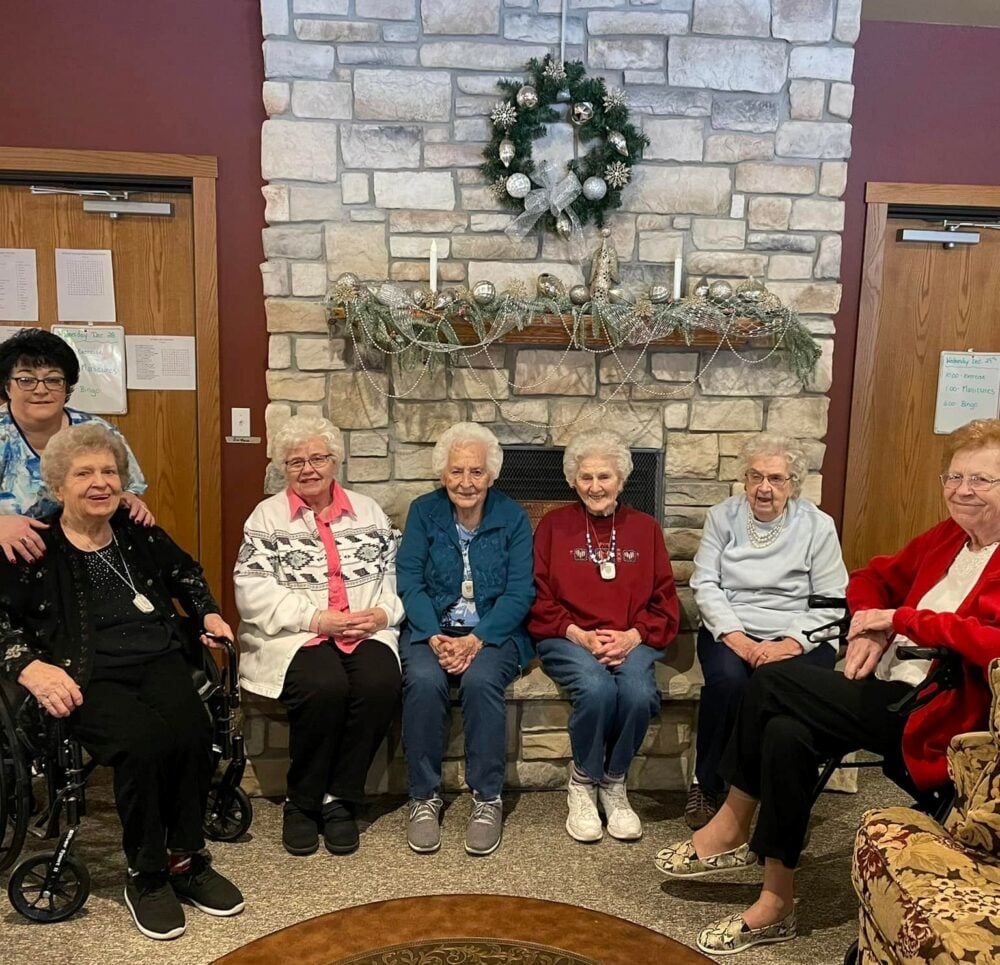 seven senior women pose together near the fireplace