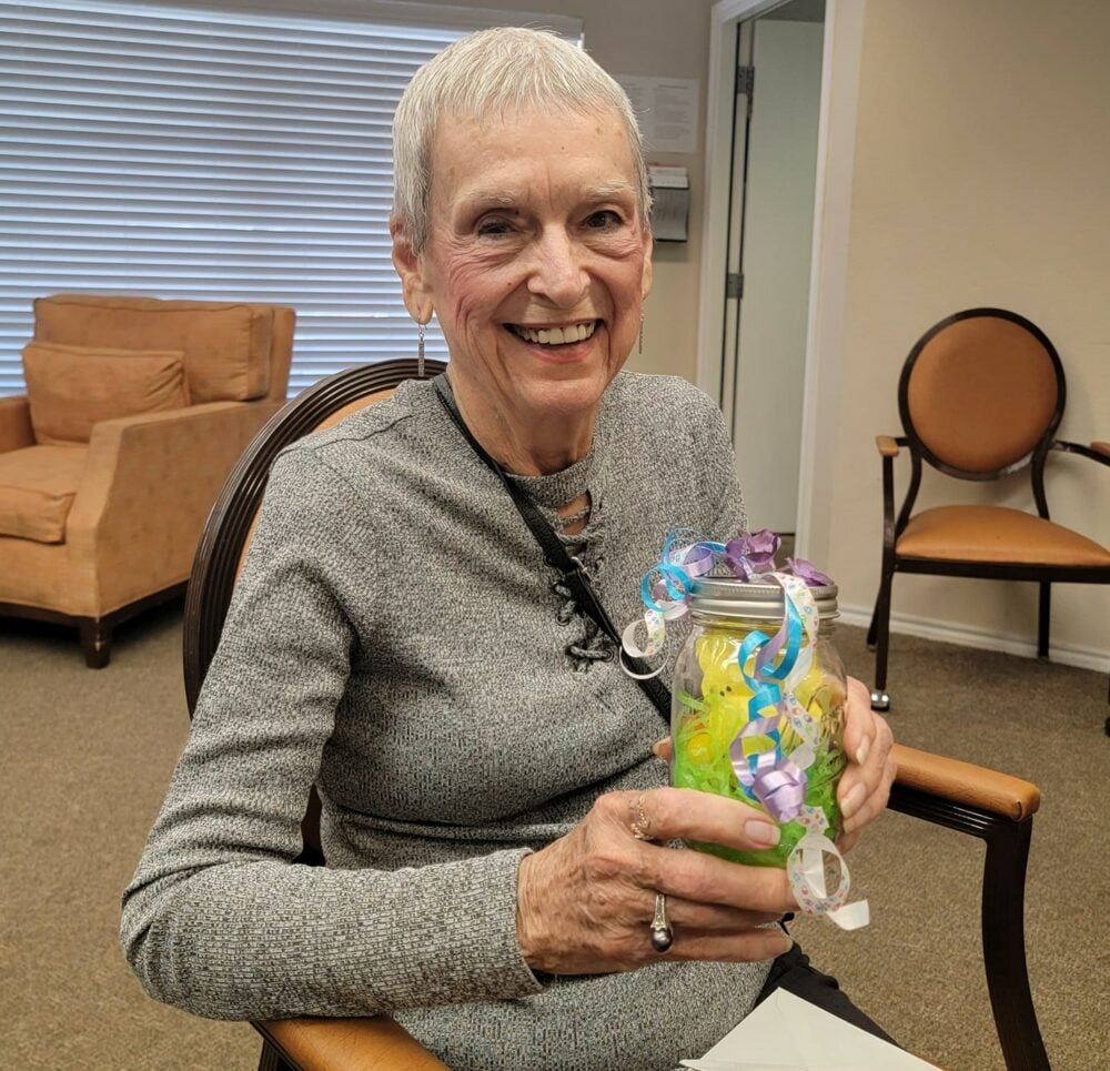 senior woman smiles and holds her decorated mason jar