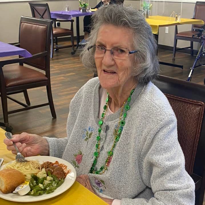 senior woman smiles while eating a meal in the dining room during mardi gras