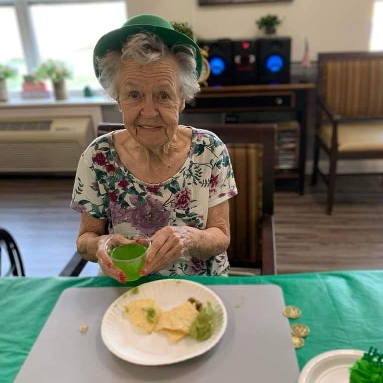 senior woman smiles while eating a St. Patrick's Day themed meal
