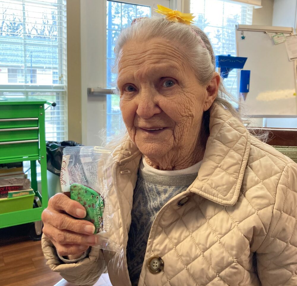 senior woman smiles while holding a green cookie