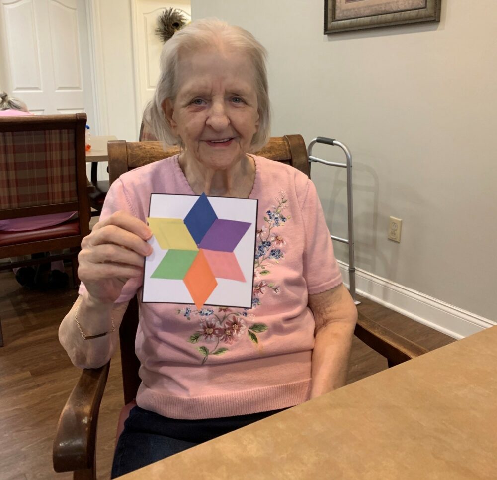 senior woman smiles and holds her completed craft project