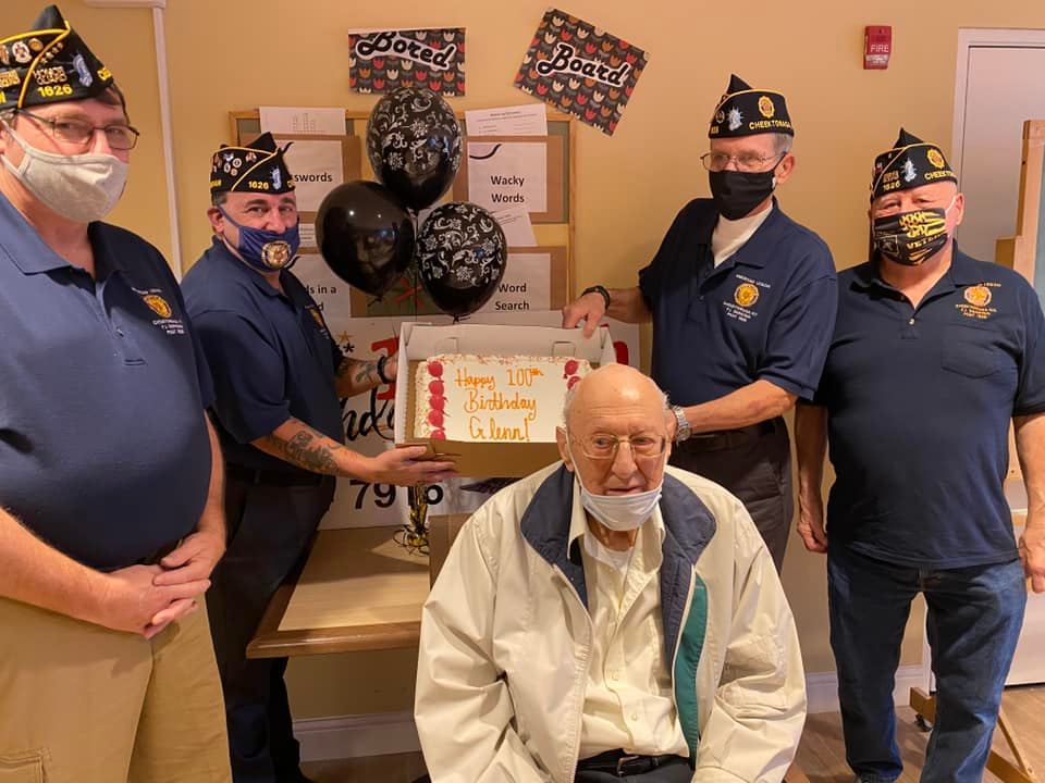 men hold a cake near a senior man celebrating his birthday