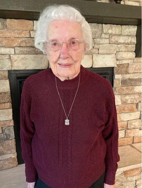 senior woman smiles for the camera in a purple sweater
