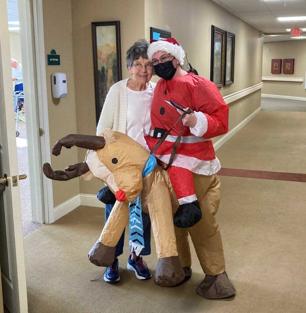 employee dressed in a festive outfit poses with a senior woman