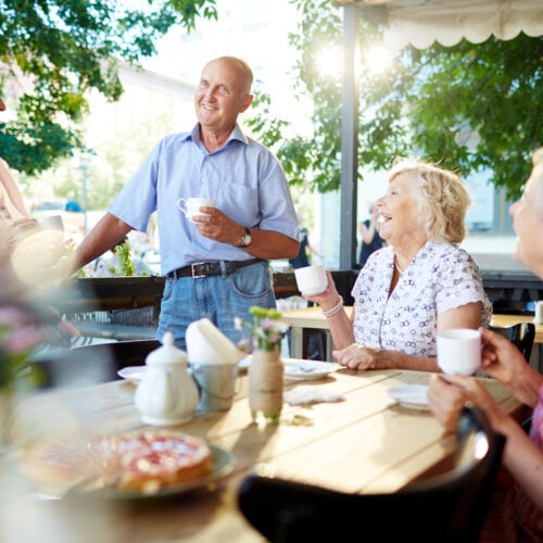 Happy senior friends having tea in cafe outside
