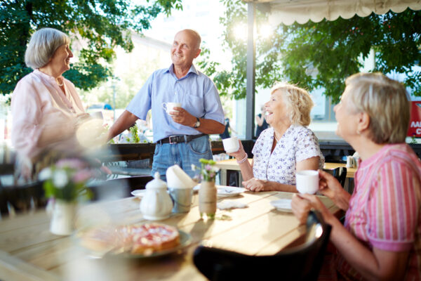 Happy senior friends having tea in cafe outside