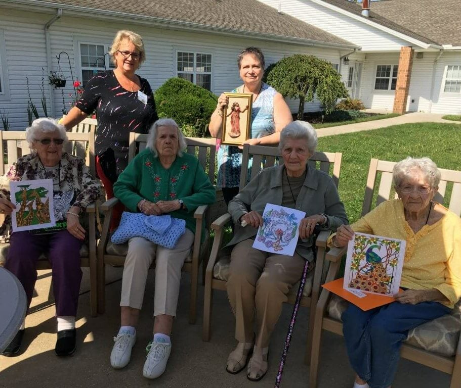 seniors sit outside and pose with their artwork