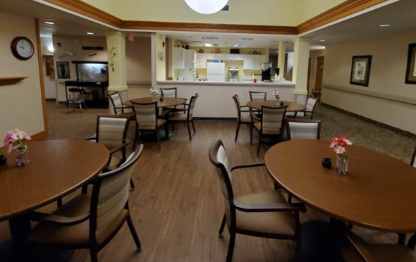 Marquis Place of Elkhorn senior living community dining room with round tables and hardwood flooring.