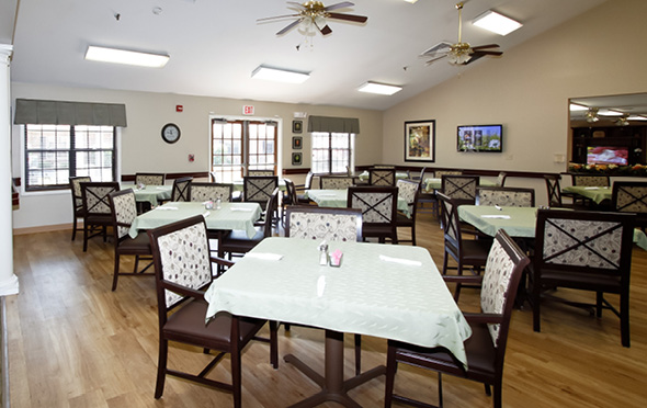 North Pointe senior living community dining room with white tablecloths on tables and high ceiling.