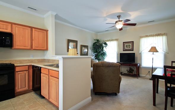 Kitchen and living room in senior living apartment with ceiling fan.