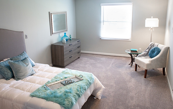 Apartment bedroom with large window at senior living community.